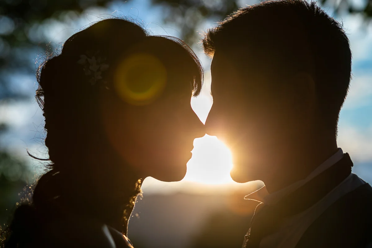 Sposi si avvicinano per un bacio, con il sole che splende dietro di loro.